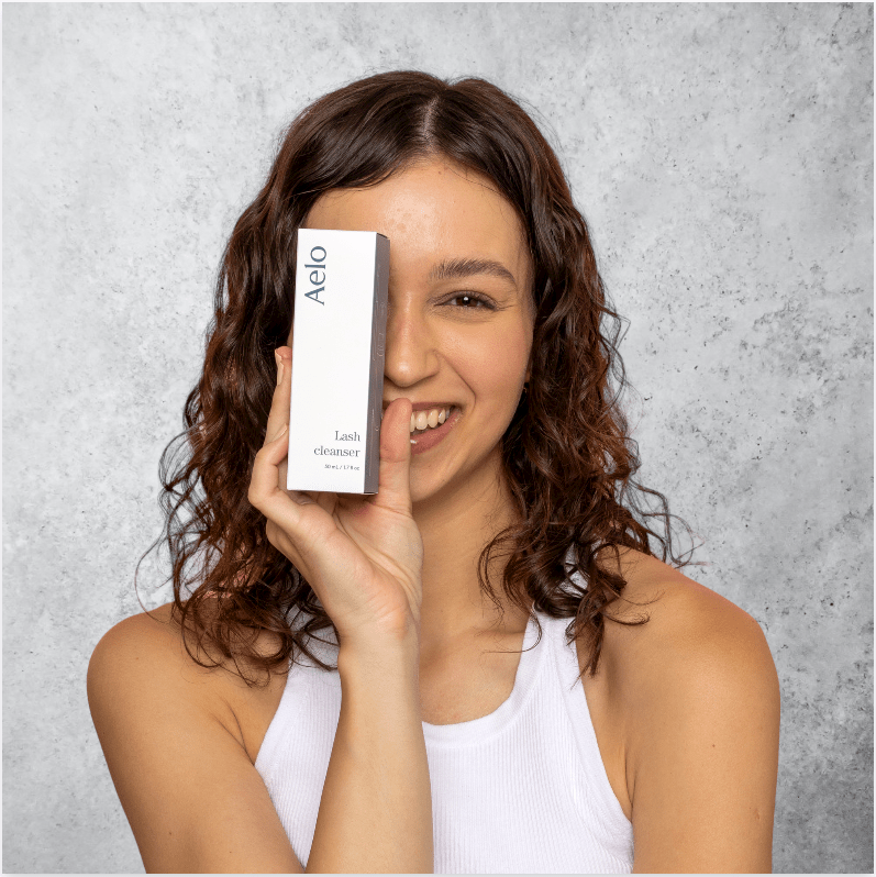female model holding aelo cleanser package on marble background