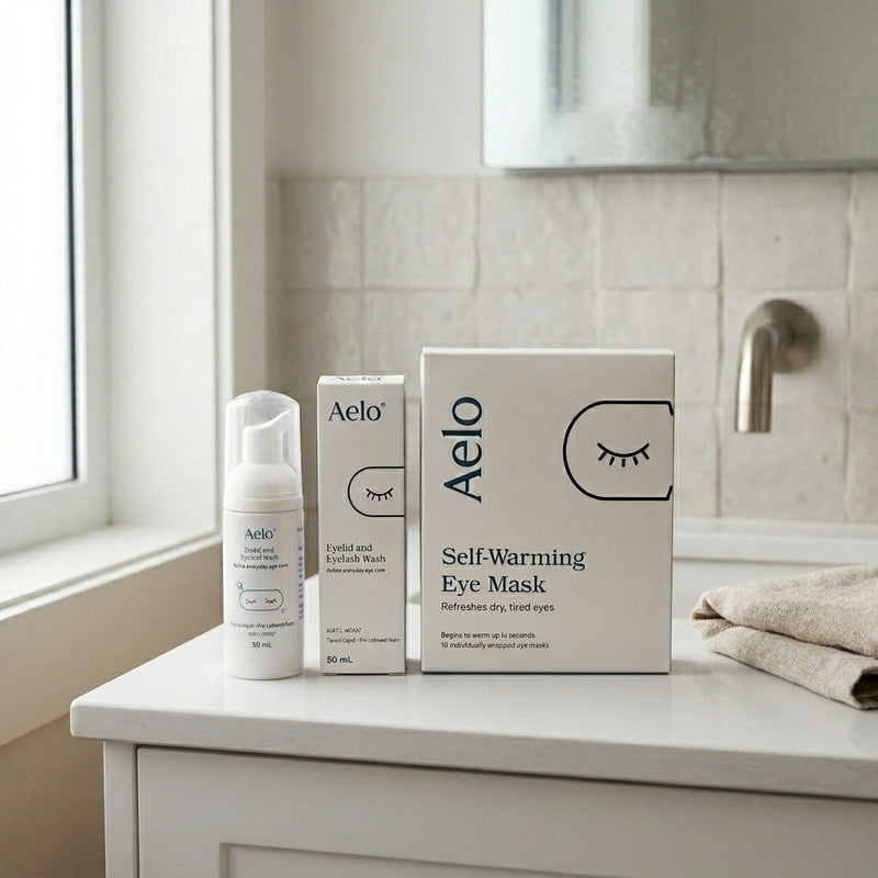 Aelo Eyelid and Eyelash Wash with a box of Aelo Self Heating Eye Masks on a bathroom vanity